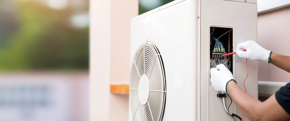 Technicien en combinaison de travail effectuant la maintenance d'une unité de climatisation extérieure