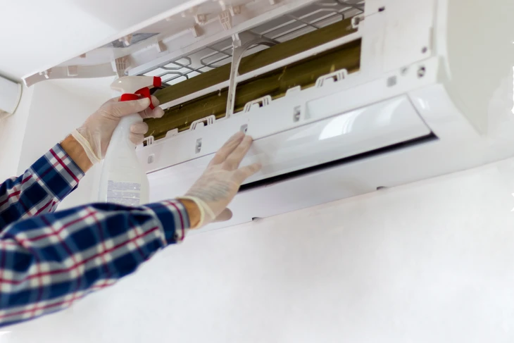 Un technicien nettoie et entretient une unité de climatisation