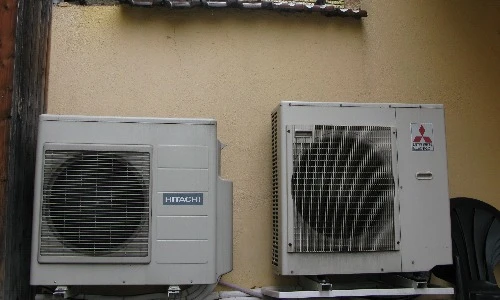 Un technicien d'ACC se tenant à côté d'un climatiseur installé à l'extérieur d'une maison