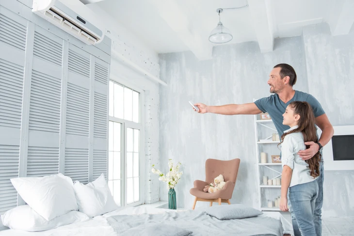 Un homme et sa fille utilisent une télécommande dans un salon moderne équipé de climatisation