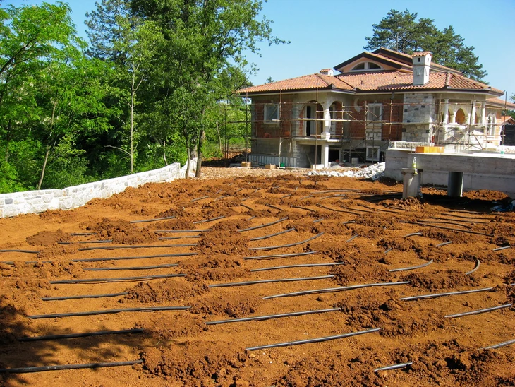 Chantier de construction résidentielle avec maison en pierre naturelle et toiture en tuiles terre cuite
