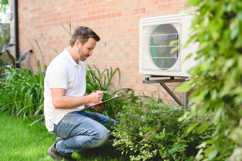 Un technicien travaillant sur la climatisation ou la pompe à chaleur d'une unité extérieure