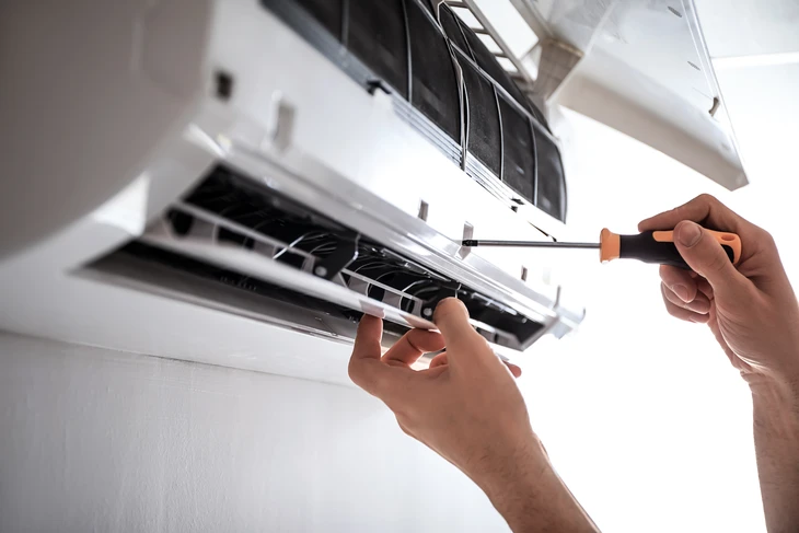 Technicien réparant une unité de climatisation murale intérieure