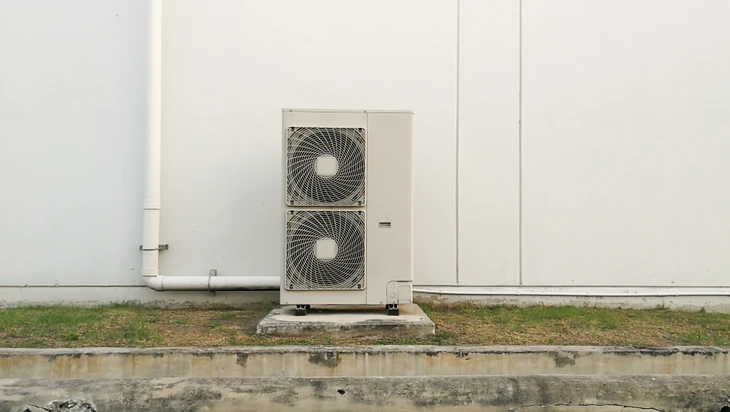 Extérieur d'un bâtiment commercial avec unité de climatisation posée sur dalle béton