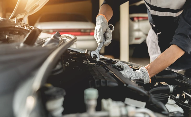 Mécanicien automobile travaillant sous le capot d'un véhicule dans un garage professionnel