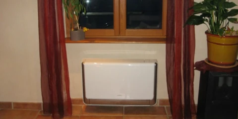 Technicien en casquette ajustant un thermostat programmable mural dans un intérieur résidentiel