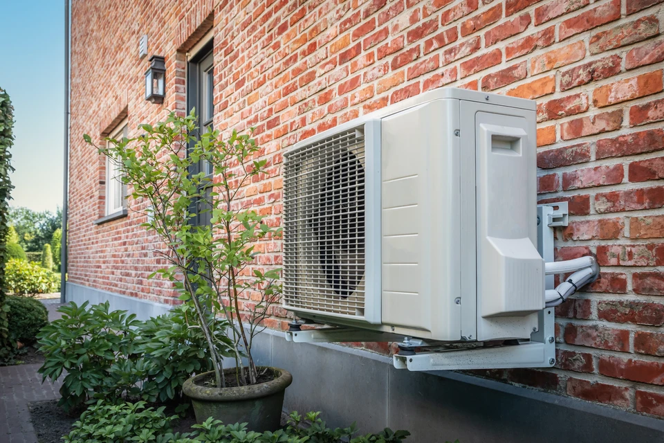 Extérieur résidentiel moderne au crépuscule avec pompe à chaleur air-eau installée sur terrasse béton