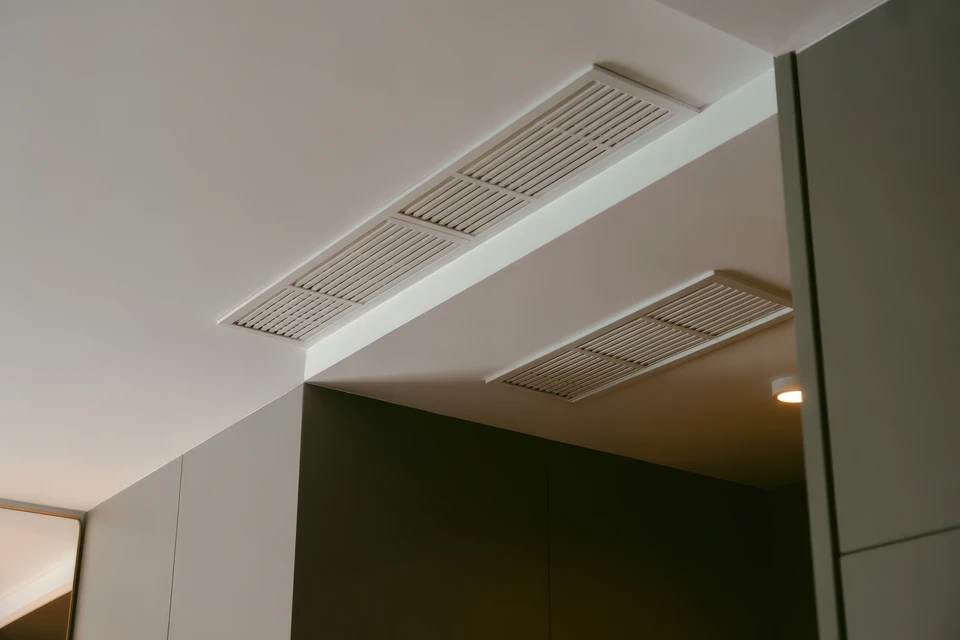 Bureau moderne avec plafond suspendu en dalles minérales perforées, éclairage par luminaires fluorescents encastrés à grilles paraboliques