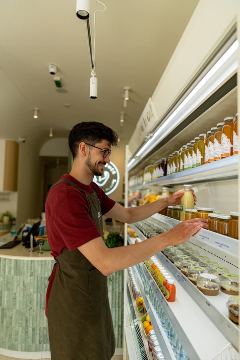 Pharmacien souriant en blouse blanche tenant un flacon de médicaments dans une officine moderne